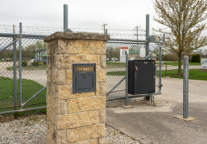 Gated entrance with keypad access and stone pillar at All Seasons Storage in Franksville, WI