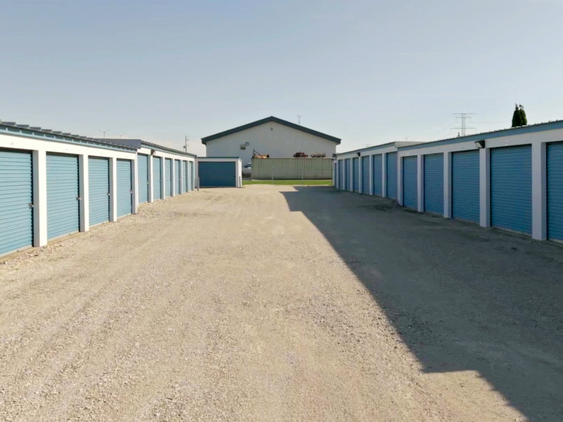 Wide gravel drive aisle between two rows of drive-up storage units near Muskego and Franklin, WI